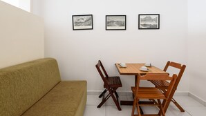 A room with a wooden table and chairs, a green sofa, and three framed black-and-white landscape photographs on the wall. - Omar do Rio - Apartamento A1202 (Rio de Janeiro)