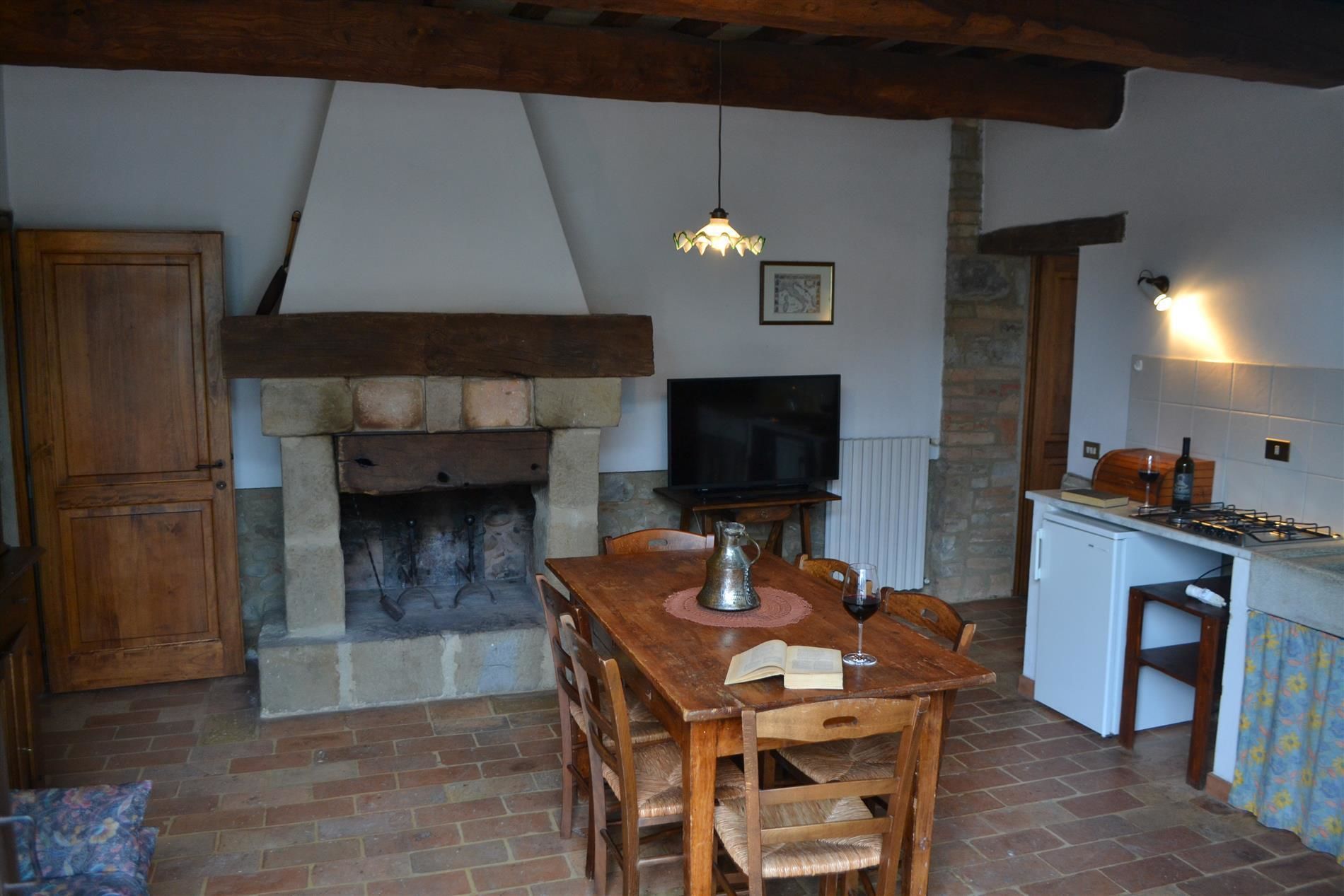 Ein gemütliches Wohnzimmer mit Kamin, Holzmöbeln, einem Fernseher und einer Küchenzeile mit Herd.
