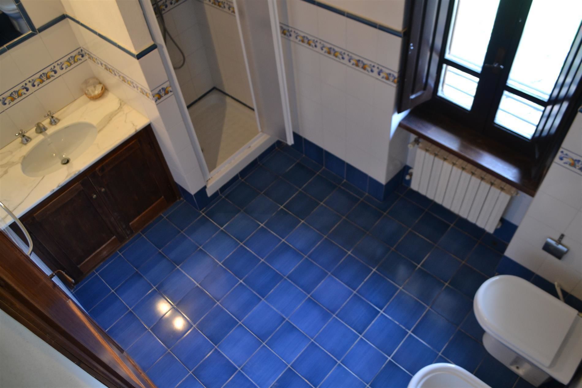 A bathroom with blue tiled flooring, a white sink, and a toilet.