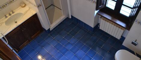A bathroom with blue tiled flooring, a white sink, and a toilet.