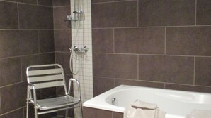 A bathroom with a shower, a bathtub, and a metal chair. - Villa Esperanza (Tongeren)