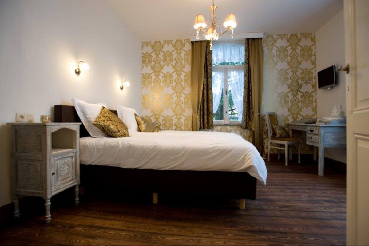 A bedroom with a bed, bedside table, and a desk.