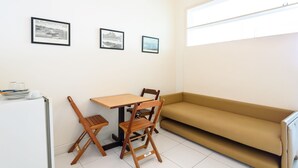Une petite pièce comprenant une table, deux chaises, un canapé et trois tableaux encadrés accrochés au mur.