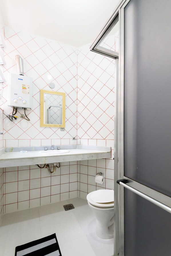 A bathroom with a white sink, toilet, and a mirror. - Omar do Rio - Apartamento A1203 (Rio de Janeiro)