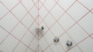 Une salle de bain avec un carrelage aux motifs géométriques et un pommeau de douche.
