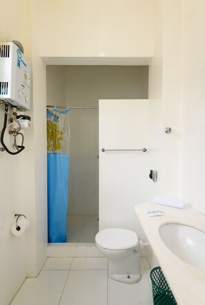 A bathroom with a toilet, a sink, a shower curtain, and a towel rack. - Apartamento A1206 - Omar do Rio (Rio de Janeiro)