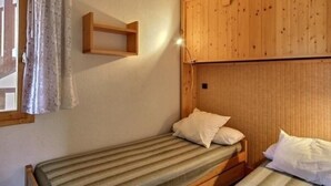 Una habitación pequeña con una cama individual, cabecera de madera y un diseño sencillo.