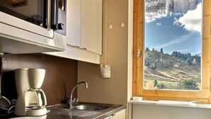 Una cocina con cafetera, lavabo y ventana con vistas al paisaje.