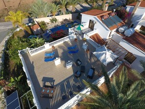 Vista aérea de una azotea con piscina, sillas de descanso y plantas en macetas.