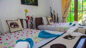 A hotel room with two beds, each with a floral bedspread and decorative pillows, including elephant and swan designs. - Hungry Lion Sigiriya (Sigiriya)