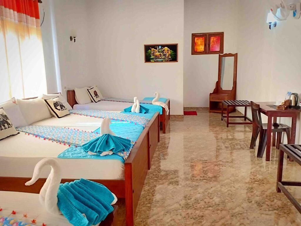 A hotel room with two beds, a dining table, chairs, a mirror, and a painting on the wall.
