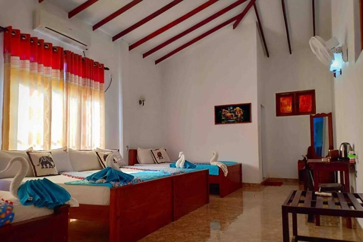 A hotel room with a large bed, two smaller beds, a desk, and a chair.