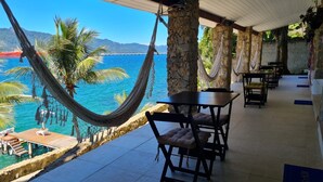 A beachside restaurant with outdoor seating, stone pillars, and a view of the ocean. - Pousada Serra e Mar (Angra dos Reis)