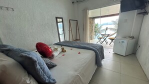 A hotel room with a bed, a small table, a chair, and a view of the outdoors. - Pousada Serra e Mar (Angra dos Reis)