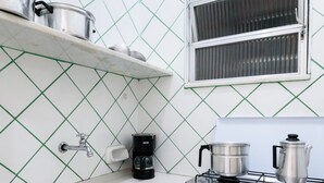 Eine kompakte Küche mit einem weißen Spülbecken, einer Kaffeemaschine und einem Gasherd.