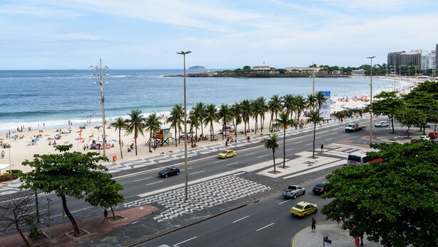 Eine Küstenstadt mit Strand, Palmen und einer belebten Straße.