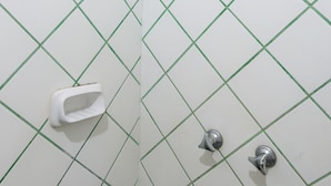 Ein gefliestes Badezimmer mit Dusche, Handtrockner und Toilette.