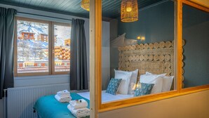 Une chambre d’hôtel avec un lit, une vue sur une montagne enneigée et une fenêtre avec des rideaux.