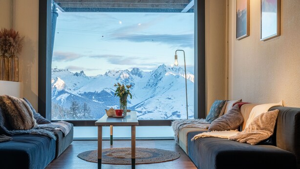 Un salon chaleureux doté d’une grande fenêtre donnant sur un paysage montagneux.