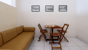 A room with a beige sofa, a wooden table with chairs, and three framed black and white photographs on the wall. - Omar do Rio - Apartamento A802 (Rio de Janeiro)
