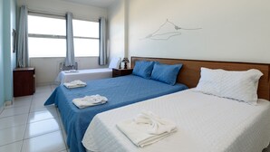 A hotel room with two beds, a large window with curtains, a wall-mounted artwork, and a bedside table with a lamp. - Omar do Rio - Apartamento A802 (Rio de Janeiro)