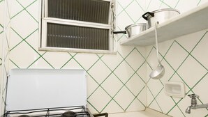 A compact kitchen with a gas stove, a sink, and a window with blinds. - Omar do Rio - Apartamento A802 (Rio de Janeiro)