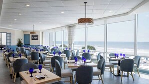 A restaurant with tables and chairs, large windows, and a view of the ocean. - Royale Palms 2307 (Myrtle Beach)