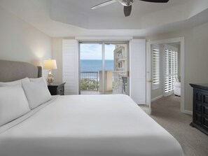 A bedroom with a bed, a nightstand, a lamp, a ceiling fan, and a view of the ocean through a sliding door. - Royale Palms 2307 (Myrtle Beach)