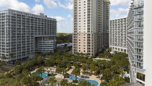 A high-rise hotel with multiple balconies, a swimming pool, and a landscaped area with palm trees. - Royale Palms 2307 (Myrtle Beach)