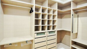 Un vestidor amplio con varias estanterías y cajones, una barra para colgar ropa y un espejo.