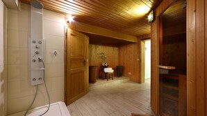 Ein Holzinnenraum mit Dusche, Holztüren und einer Bank.