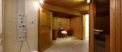 Un interior de madera con ducha, puertas de madera y una banca.