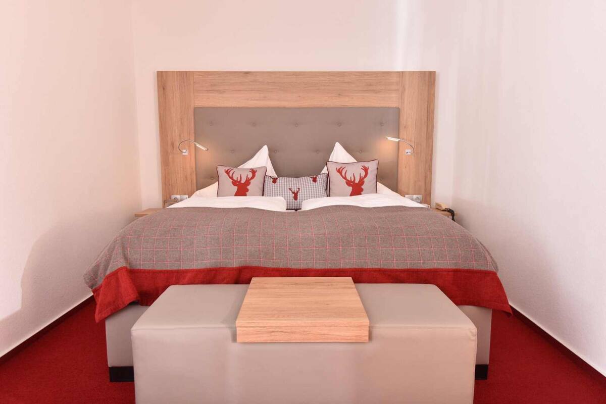A neatly arranged bedroom with a wooden headboard, a checkered bedspread, and matching pillows.