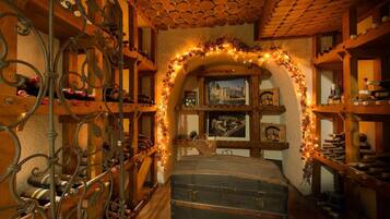 Une cave à vin avec des étagères en bois, un grand coffre et une arche décorative.