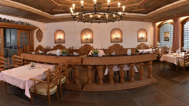 Ein Restaurant mit einer zentralen Bar, Holzsesseln und Tischen, gedeckt für das Essen.