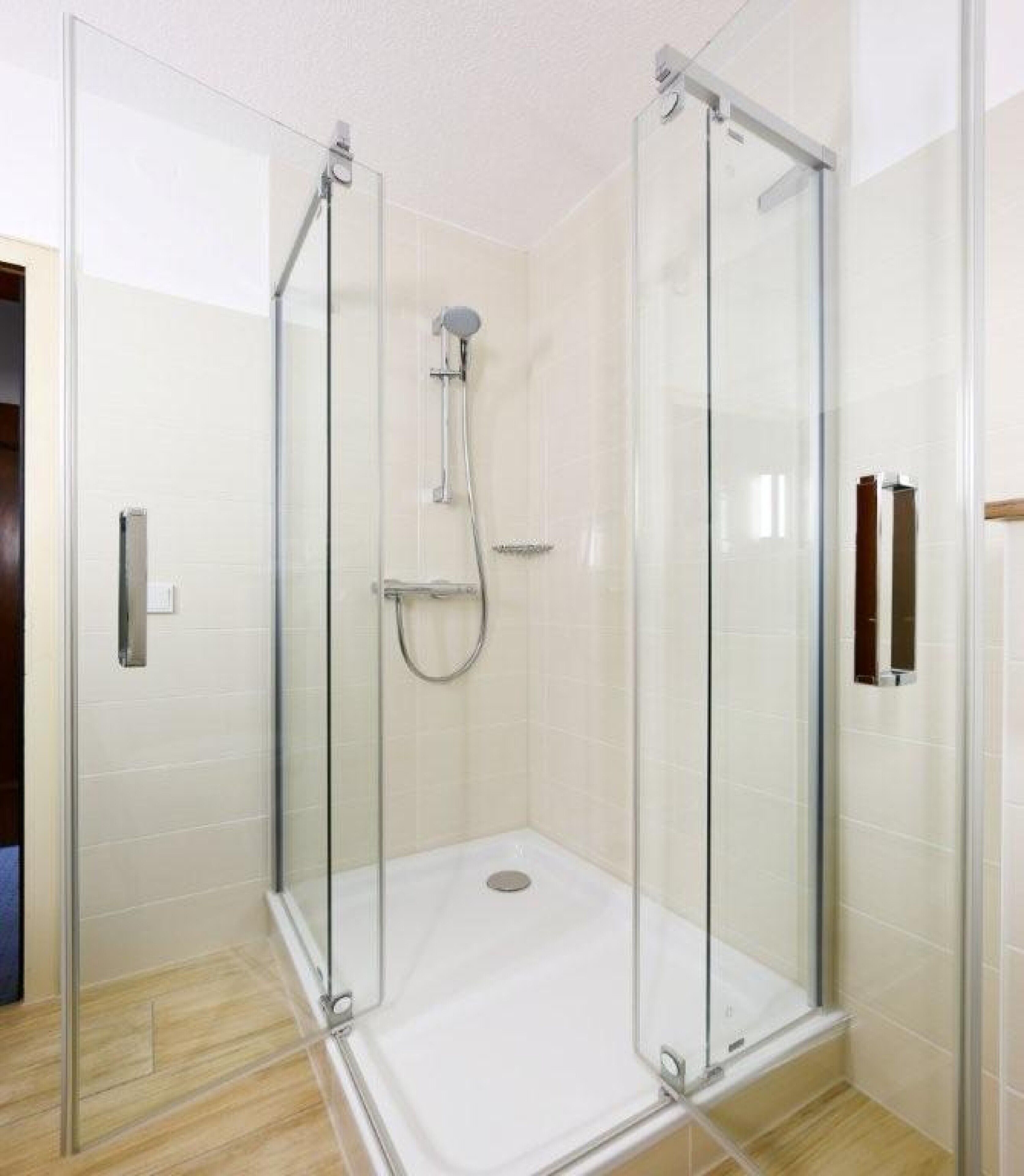 Eine begehbare Duschkabine mit Handbrause und am Wand montiertem Wasserhahn.