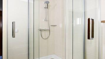 Eine begehbare Duschkabine mit Handbrause und am Wand montiertem Wasserhahn.