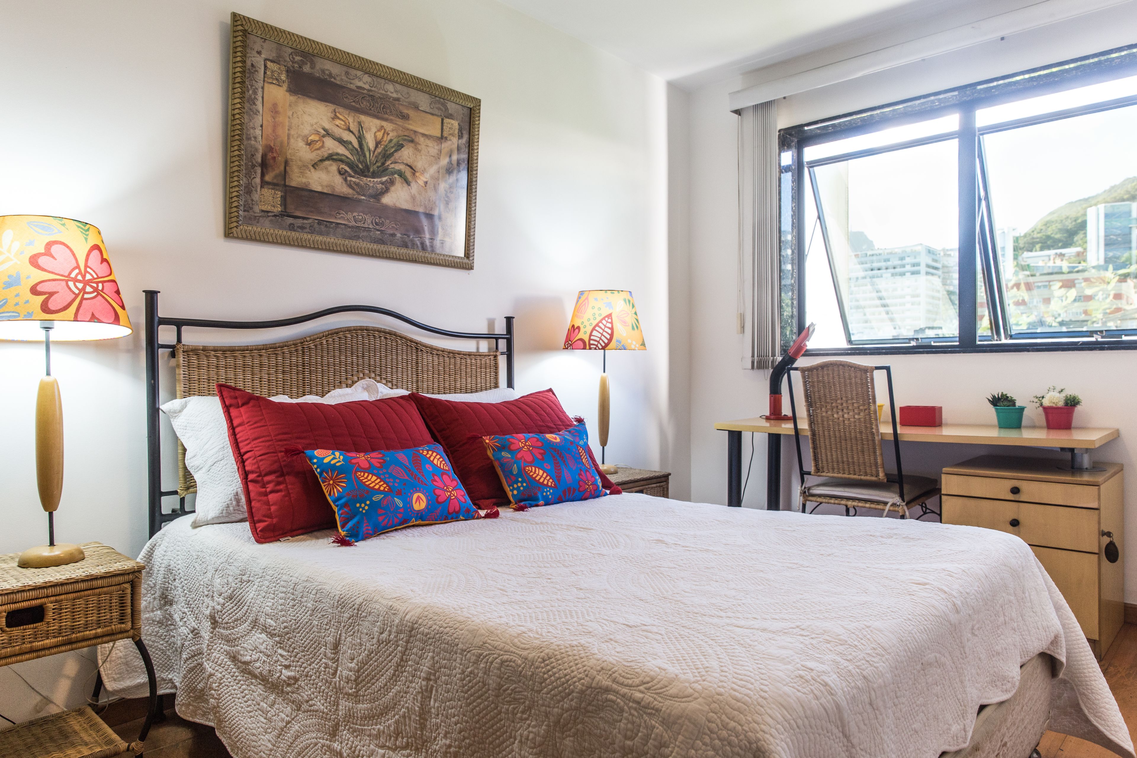 A neatly arranged bedroom with a bed, two bedside tables, a desk, and a chair.