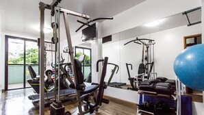 Une salle de sport équipée de divers appareils d’exercice, dotée d’un mur avec des miroirs et d’un grand ballon d’exercice.