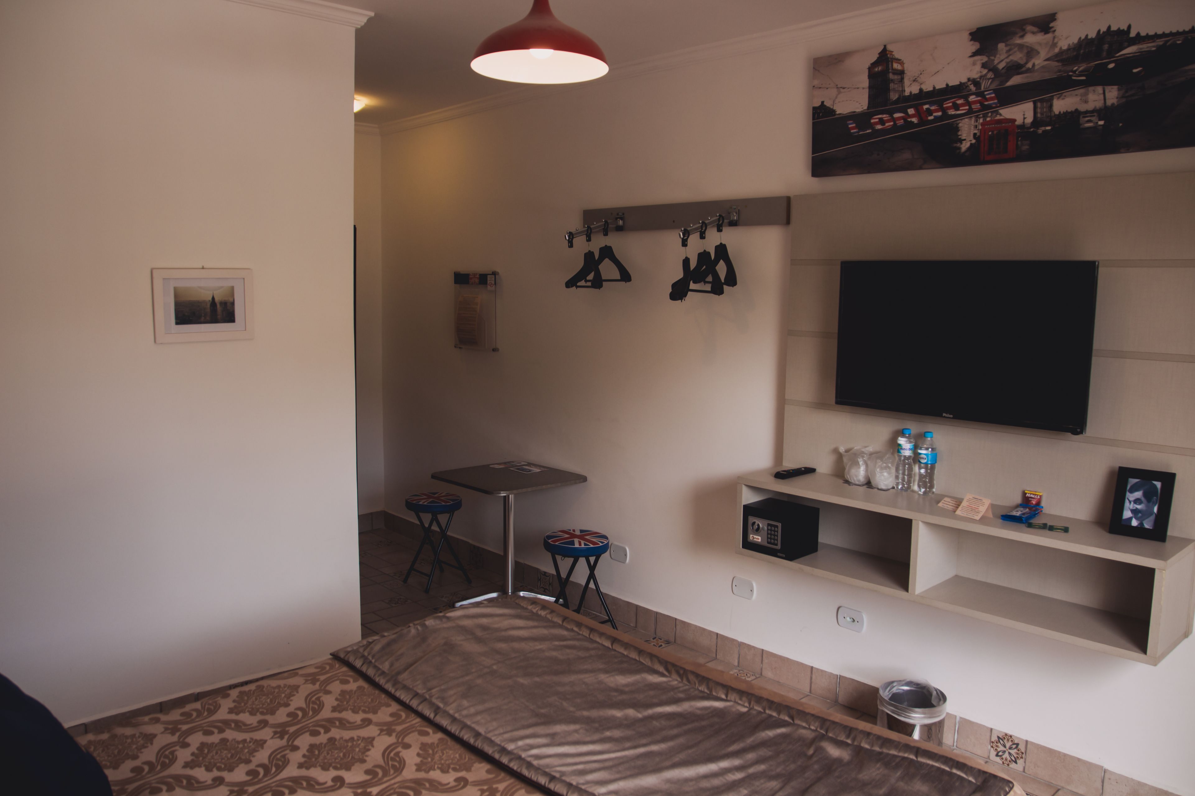 Un dormitorio con una cama, un escritorio, una silla, un televisor y una estantería con objetos.