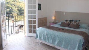 A bedroom with a bed, a nightstand, a lamp, and a view of a balcony with a railing. - Hotel Casarão da Ducha (Campos do Jordão)