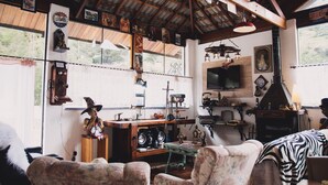 A rustic interior with wooden beams, a television, and various decorative items. - Hotel Casarão da Ducha (Campos do Jordão)