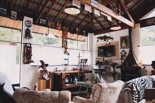 Um interior rústico com vigas de madeira, uma televisão e diversos objetos decorativos.