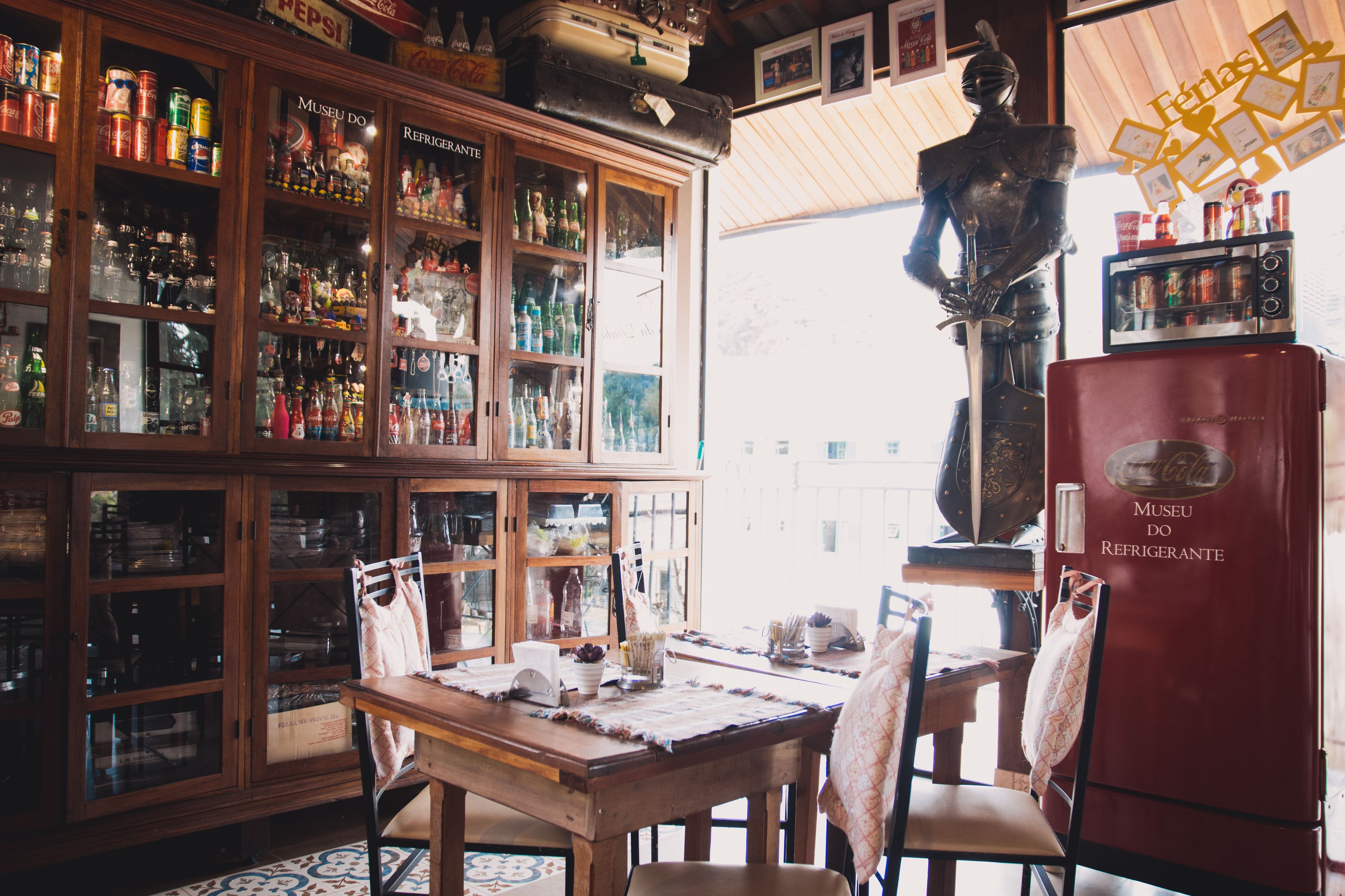A bar area with wooden cabinets filled with bottles, a red refrigerator, and a statue.