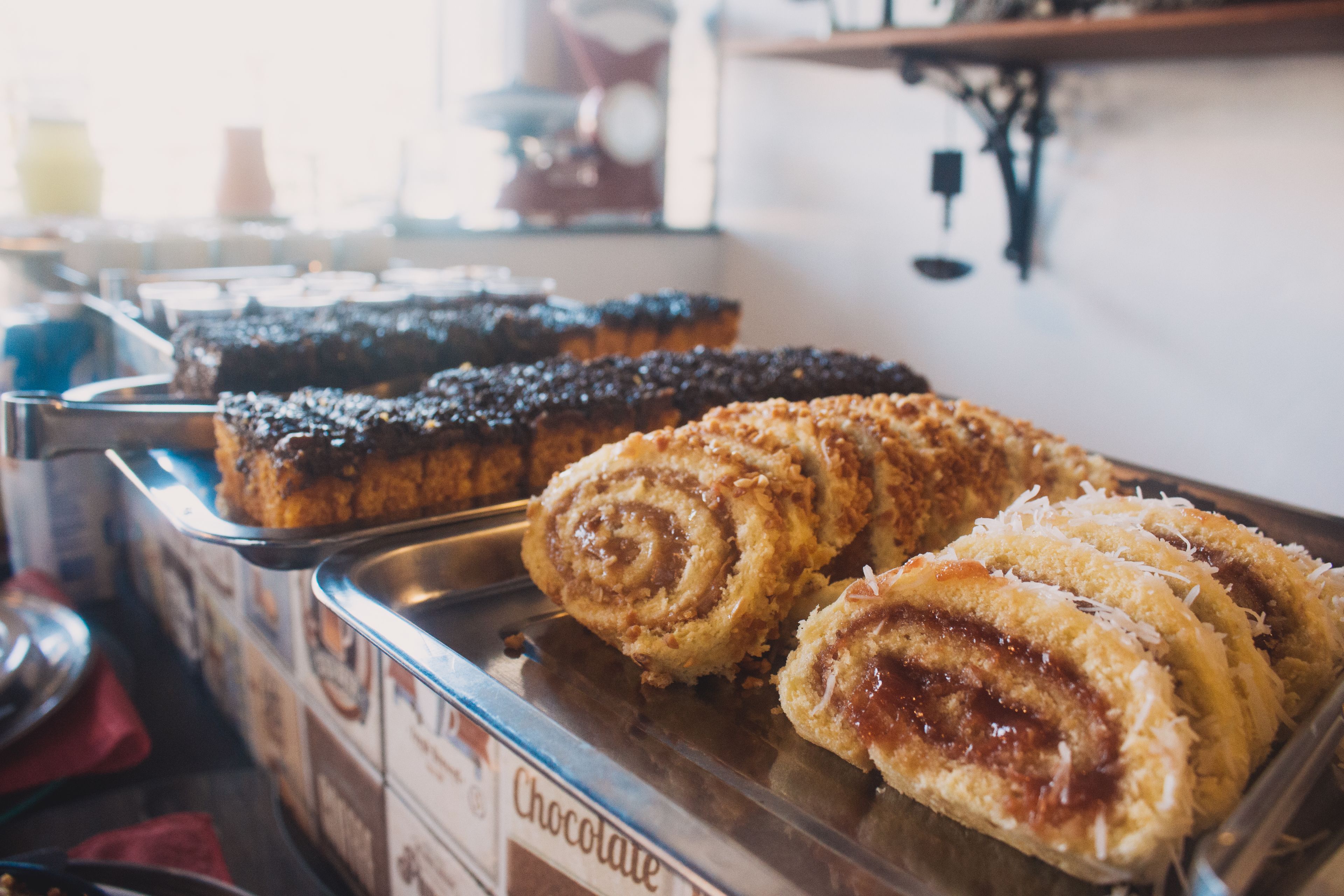 A display of various pastries, including chocolate and cinnamon rolls, in a bakery setting.