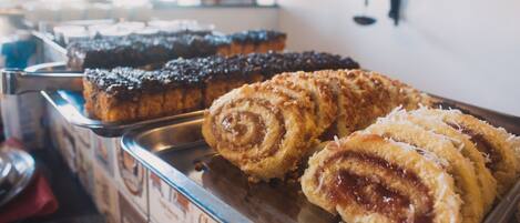 A display of various pastries, including chocolate and cinnamon rolls, in a bakery setting.