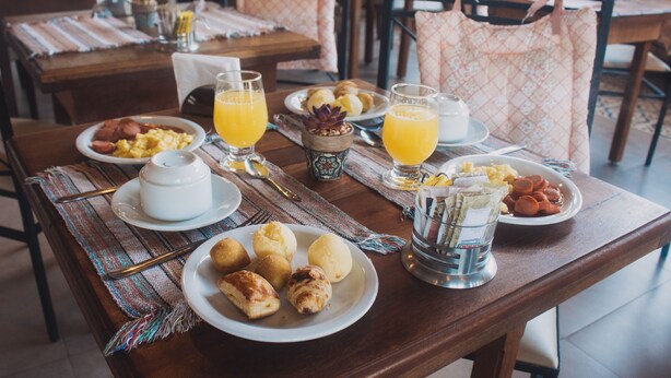 A breakfast table with plates of food, glasses of orange juice, and a small decorative bowl. - Hotel Casarão da Ducha (Campos do Jordão)