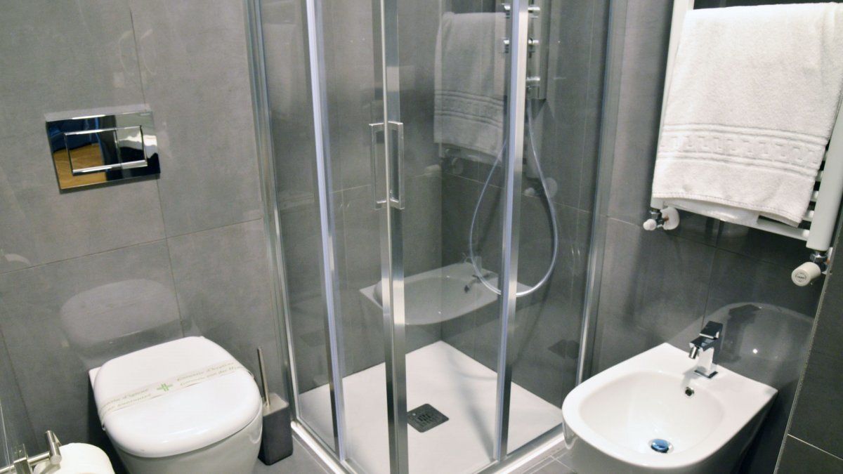 Un baño moderno con ducha de mampara de vidrio, inodoro y lavamanos.