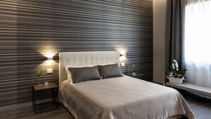 A modern bedroom with a large bed, two bedside tables with lamps, a window with curtains, and a wall with horizontal lines. - Borea Luxury B&B (Pescara)