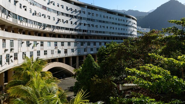 Un edificio de varios pisos con fachada curva, múltiples balcones y un arco central.